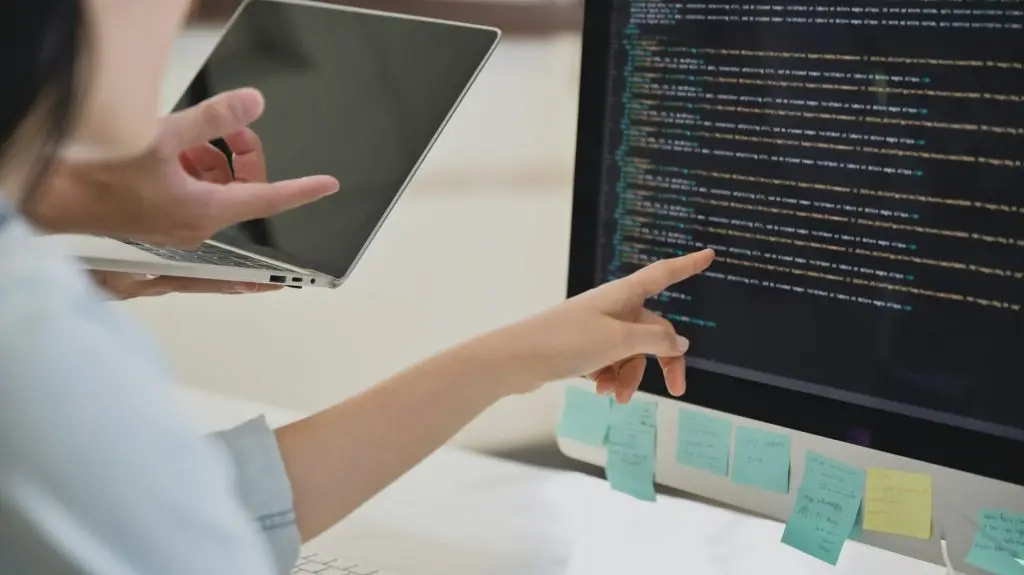 A team of programmers are checking the code on the computer screen.